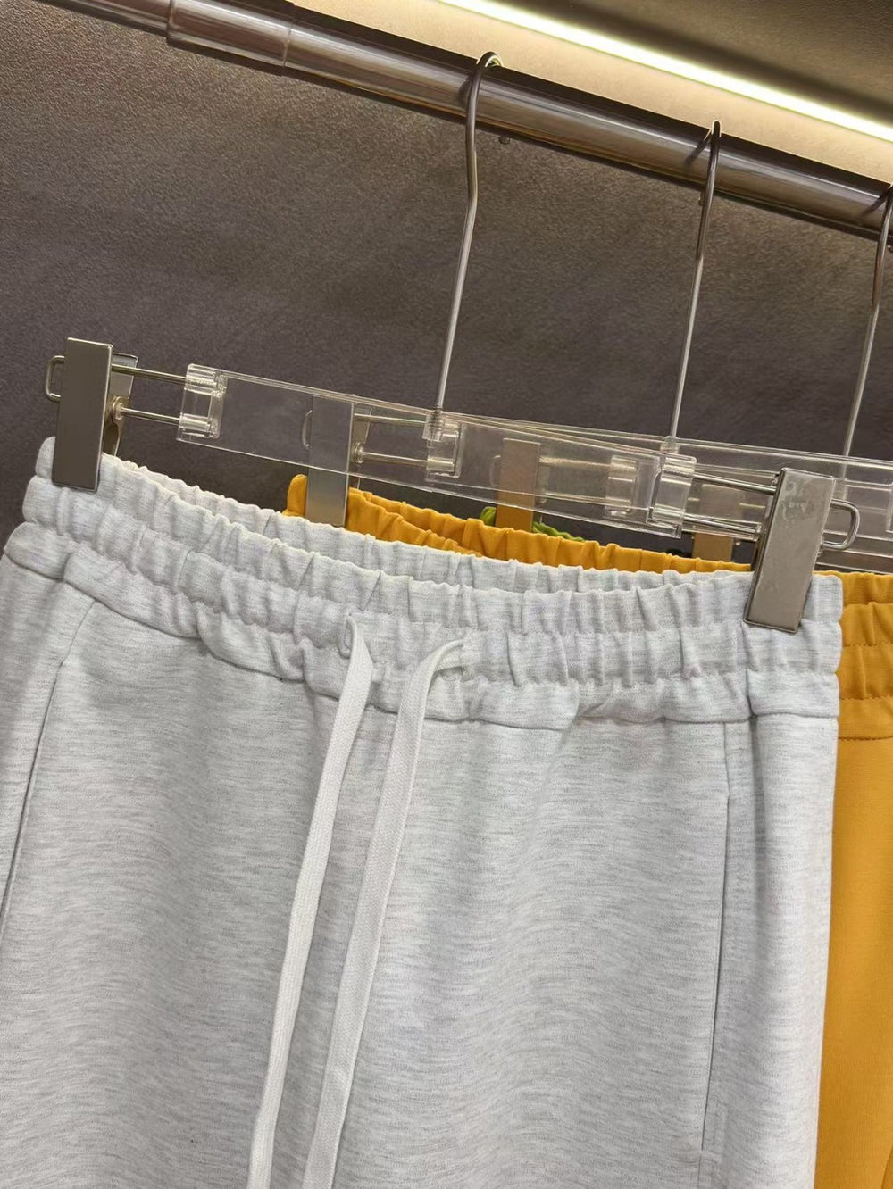 Ralph Lauren Women's Pony Straight Leg Pants. Gray sweatpants hanging on a rack with yellow pants partially visible.