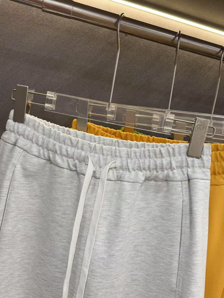 Ralph Lauren Women's Pony Straight Leg Pants. Gray sweatpants hanging on a rack with yellow pants partially visible.