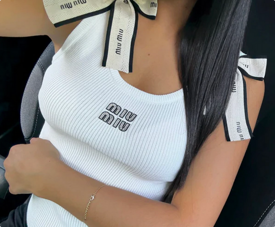 White ribbed chic knot top with 'Miu Miu' branding worn by a woman. 