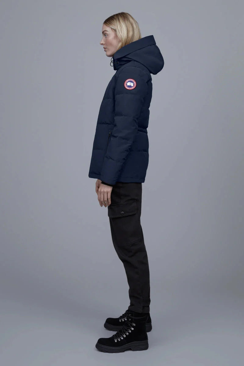 Woman wearing a navy blue Canada Goose Chelsea Parka Women's Down Winter Jacket at Volonka store. coat with a brand logo.
