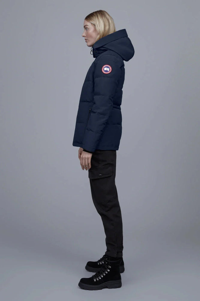 Woman wearing a navy blue Canada Goose Chelsea Parka Women's Down Winter Jacket at Volonka store. coat with a brand logo.