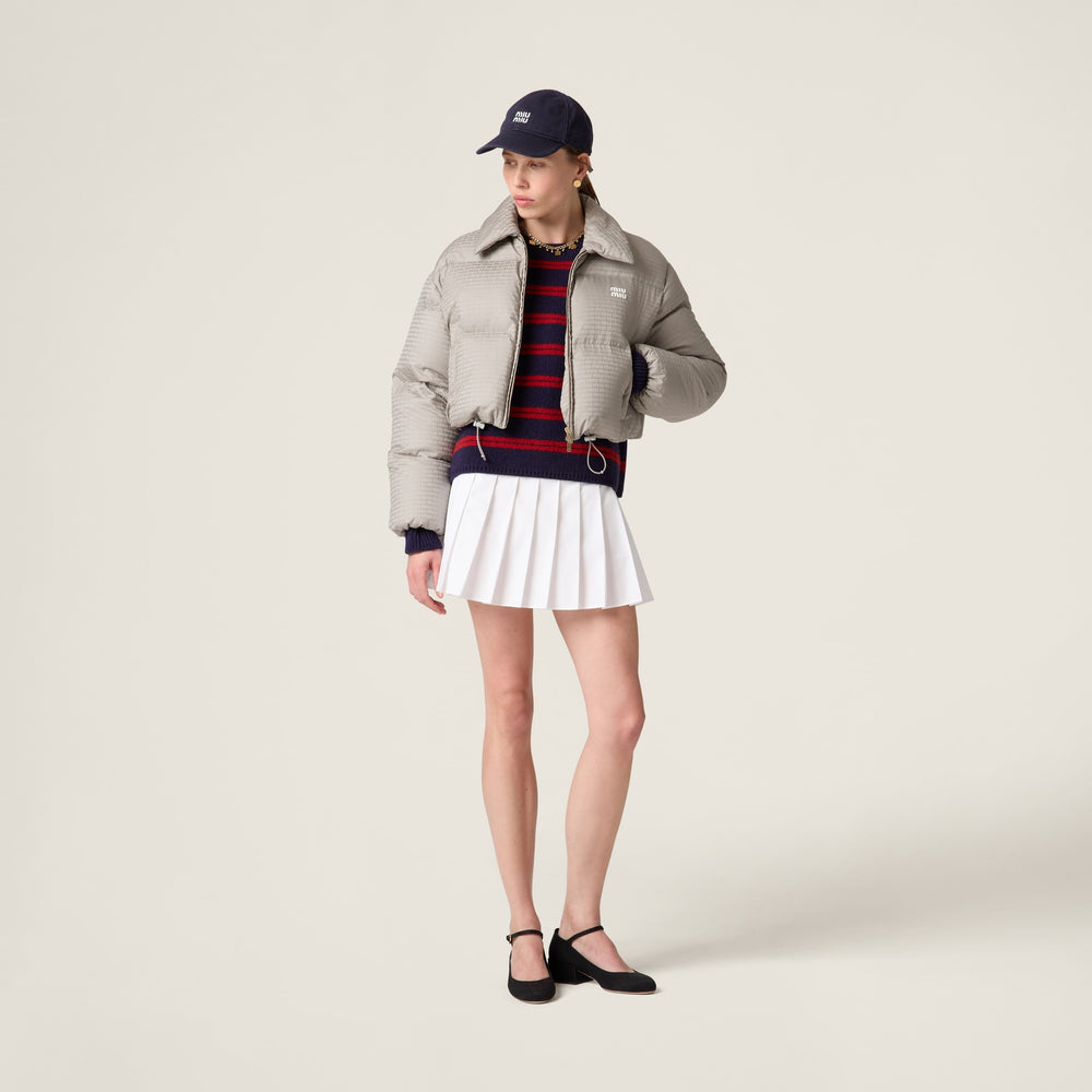 MIUMIU beige jacket, striped sweater, and white pleated skirt on a plain background