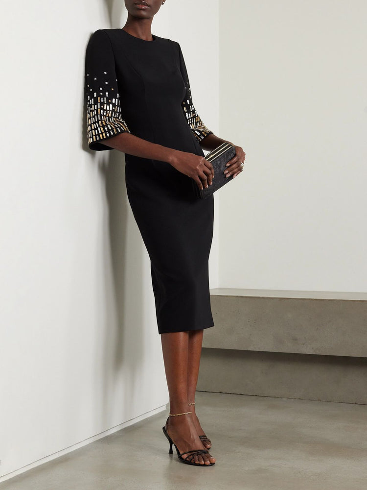 Woman wearing a black dress with patterned sleeves against a white wall. Black Short Sleeve Crystal Midi Dress for Women at Volonka.