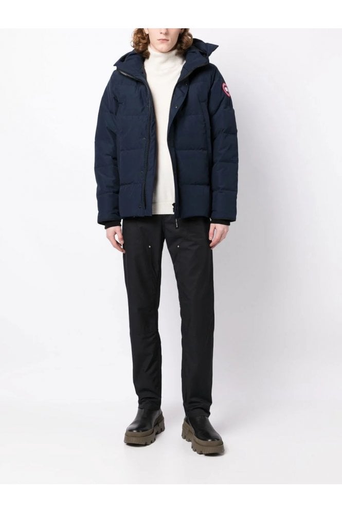 Person wearing a navy blue jacket, white shirt, black pants, and dark shoes on a white background. Women's/ men Canada Goose Wyndham Parka with Fur jacket