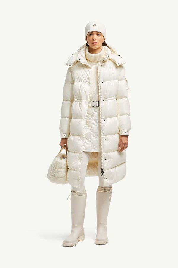 Person wearing a long white puffer coat with a matching hat and boots. Moncler Cavettaz Hooded Long Down Jacket