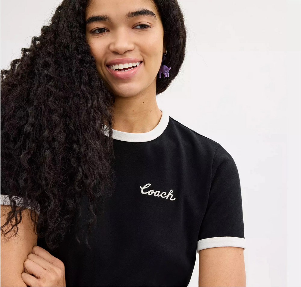 woman wearing a black 'Coach' t-shirt on a white background