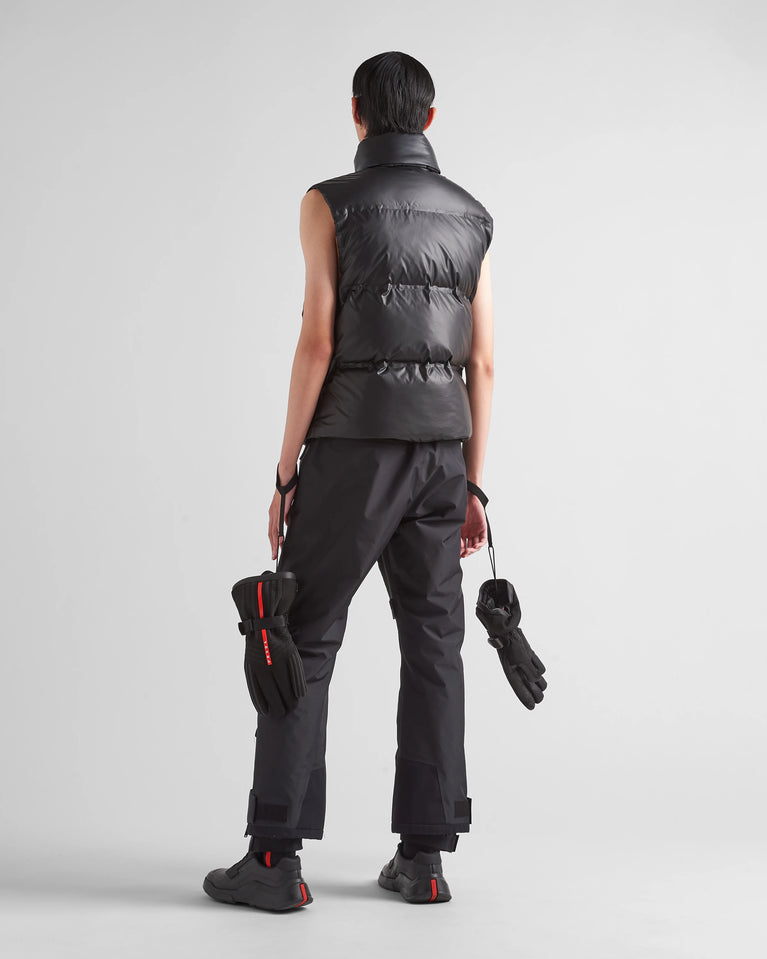 Prada Men's light Down Vest jacket, man wearing a black puffer vest, pants, and gloves on a light gray background
