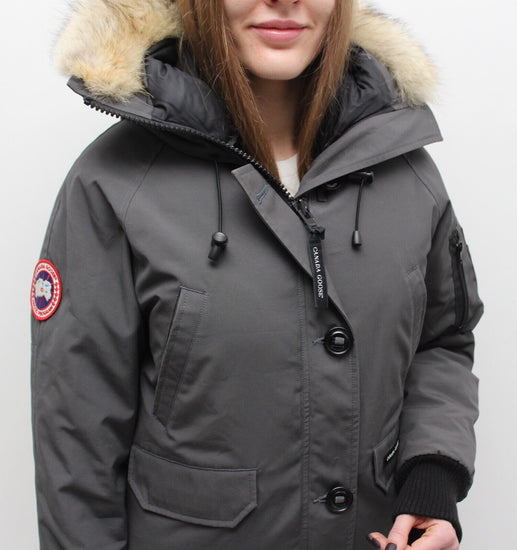 woman wearing a gray parka with a fur-lined hood on a white background