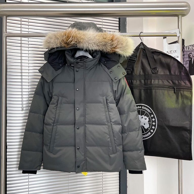 Gray winter jacket with fur hood on a rack next to a Canada Goose bag. Women's/ men Canada Goose Wyndham Parka with Fur jacket