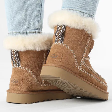 Brown UGG boots with white fur lining worn with light blue jeans on a white background